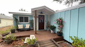 Una casa con porche, buzón y puerta decorada con un adorno navideño.