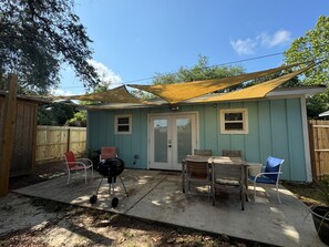 A backyard with a covered patio, a barbecue grill, and outdoor seating.