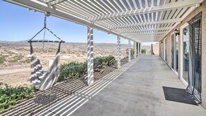 A covered outdoor area with a hammock, a concrete walkway, and a view of the desert landscape. - Beautiful Hemet Home: Large Patio & Mtn Views! (Hemet)