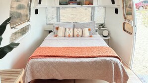 A compact, well-lit interior with a bed, a small table, and a window.