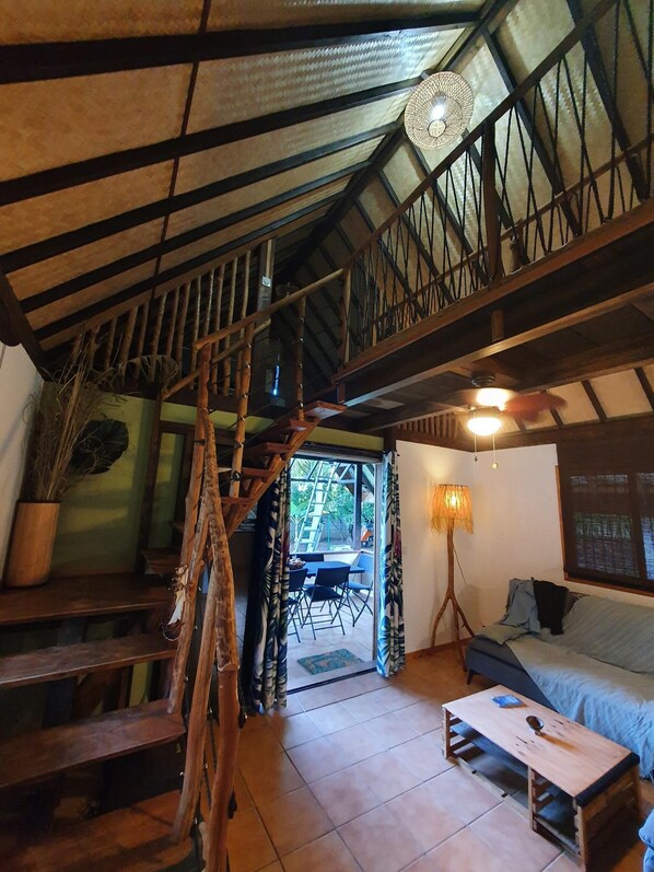 A rustic interior with a wooden staircase, a dining area, and a cozy seating space.