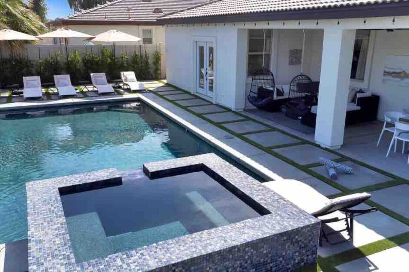 A swimming pool with a hot tub, lounge chairs, and a patio area with outdoor furniture.