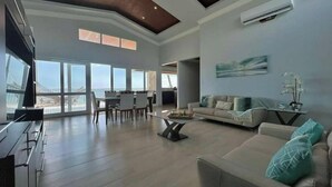 Un salón amplio con un gran ventanal, un sofá, una mesa de centro y un televisor.