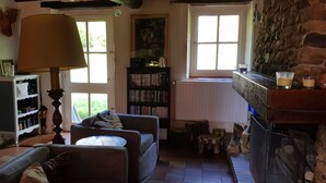 A cozy living room with a fireplace, a bookshelf, a sofa, and a lamp. - Pretty country house with large garden (Diges)