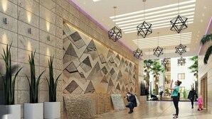 Un vestíbulo moderno con patrones geométricos en las paredes, lámparas colgantes geométricas y plantas en macetas.