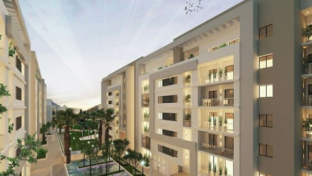 Un hotel moderno de varios pisos con balcones, piscina en la azotea y jardines ajardinados.
