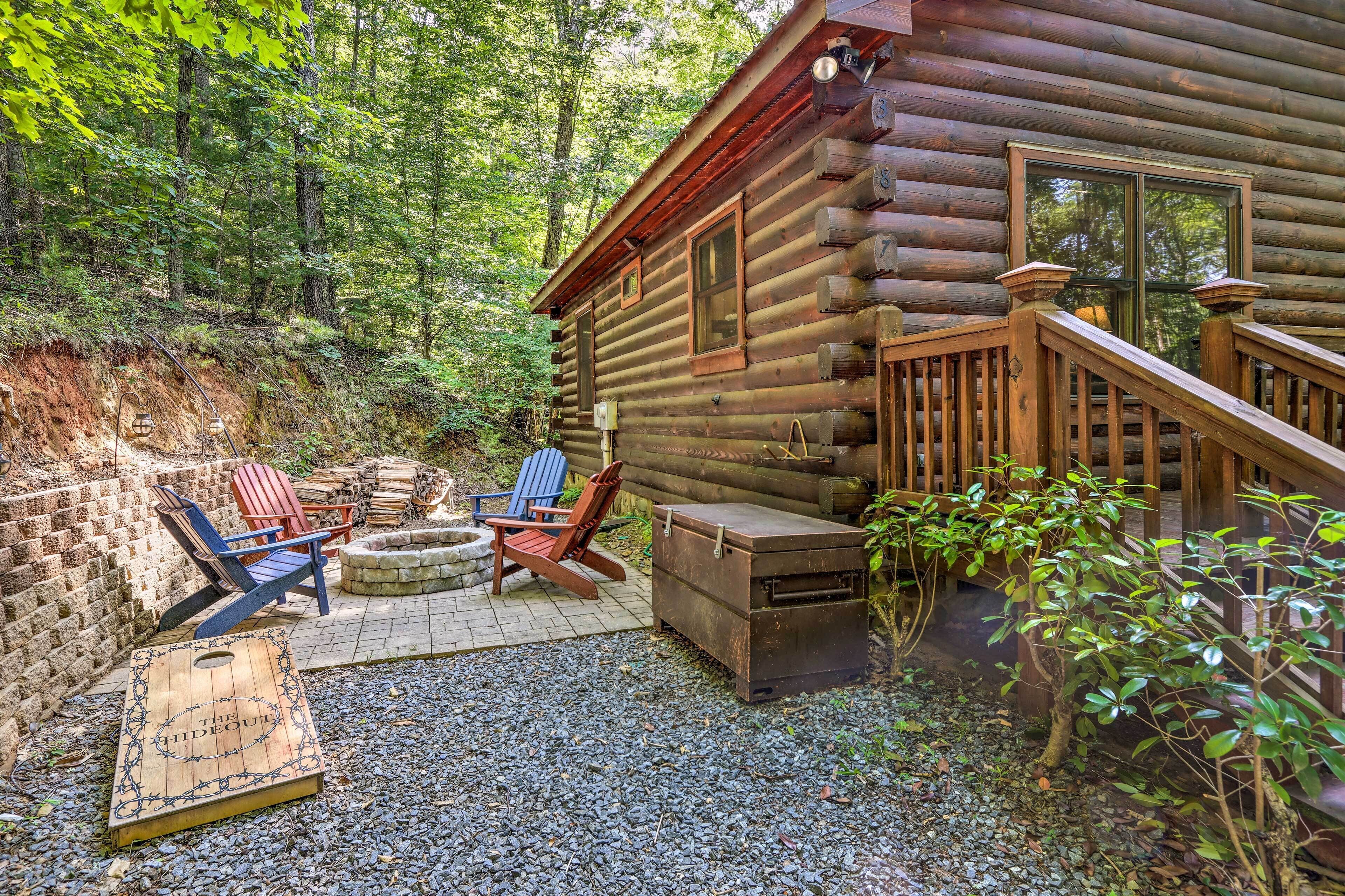 A log cabin with a deck, outdoor seating, and a fire pit.