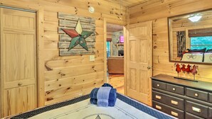 A wooden cabin interior with a star decoration, a ceiling fan, a dresser, and a mirror reflecting a star decoration. - 'Bigfoot's Hideout' in Blue Ridge w/ Hot Tub! (Blue Ridge)
