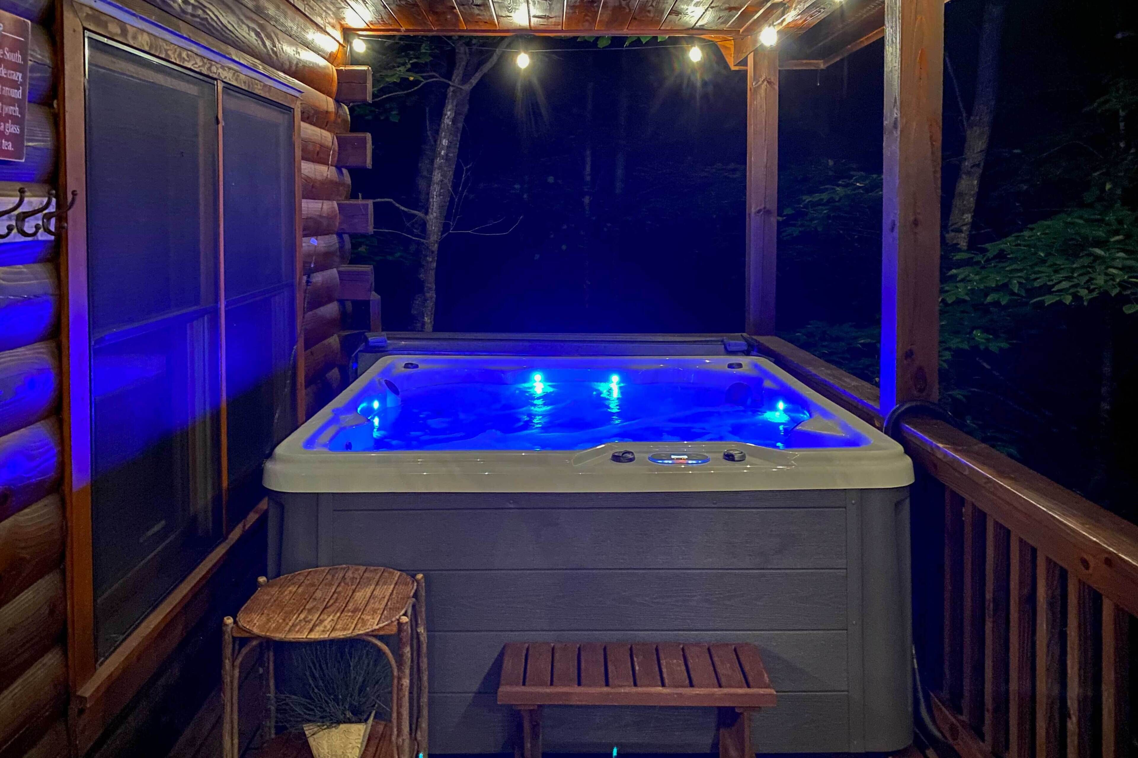 Una cabaña de madera con un jacuzzi, un banco de madera pequeño y una puerta de cristal.