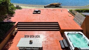 Terraza en la azotea con un jacuzzi, una mesa y sillas, con vistas a un lago y una orilla boscosa.