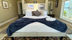 Un dormitorio amplio con una cama grande, vistas al exterior y obras de arte en las paredes.