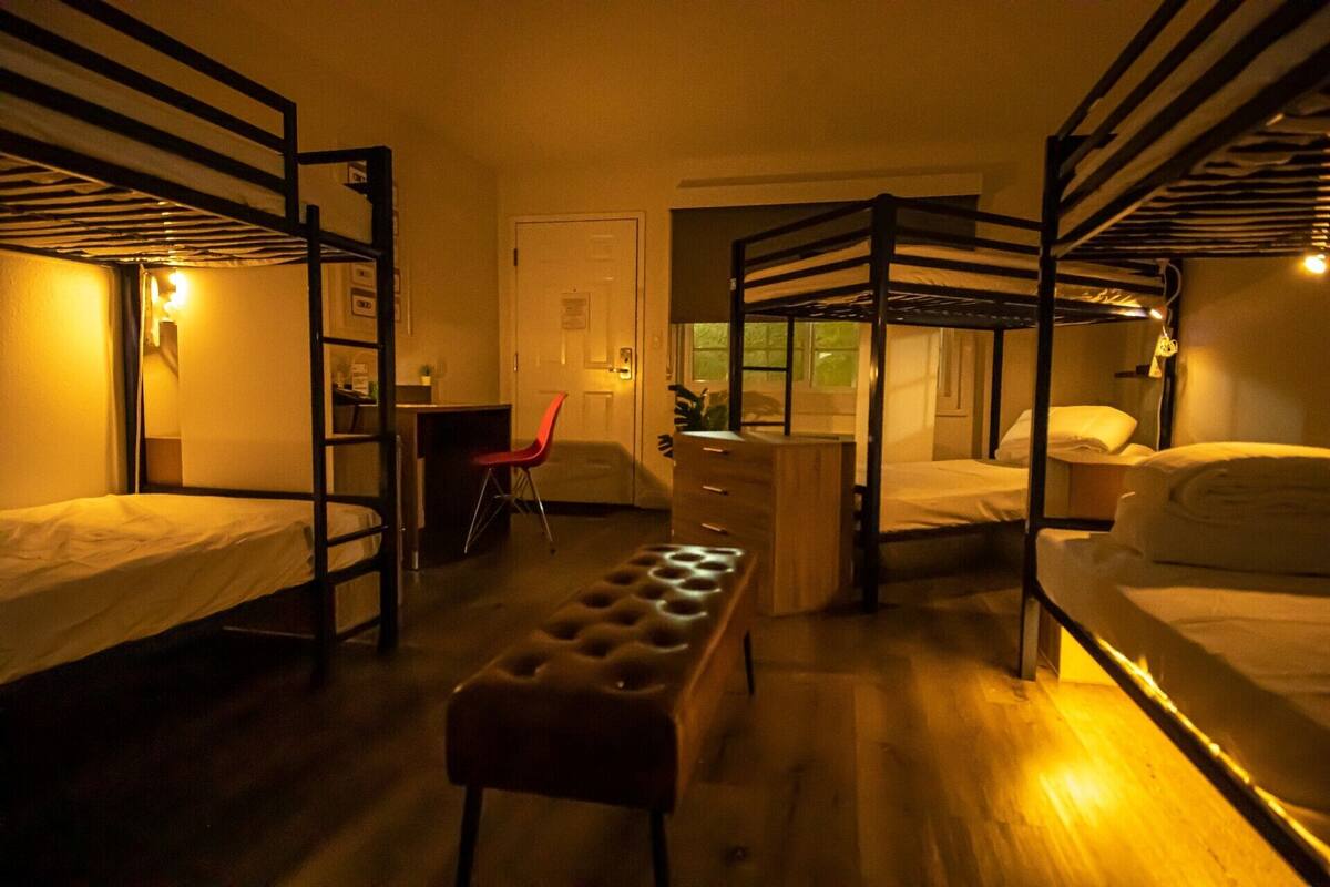 Une chambre de dortoir équipée de lits superposés, d’un bureau, d’une chaise et d’un banc.