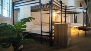 A bunk bed room with a wooden desk, a potted plant, and a window. - Bposhtels Anaheim (Anaheim)