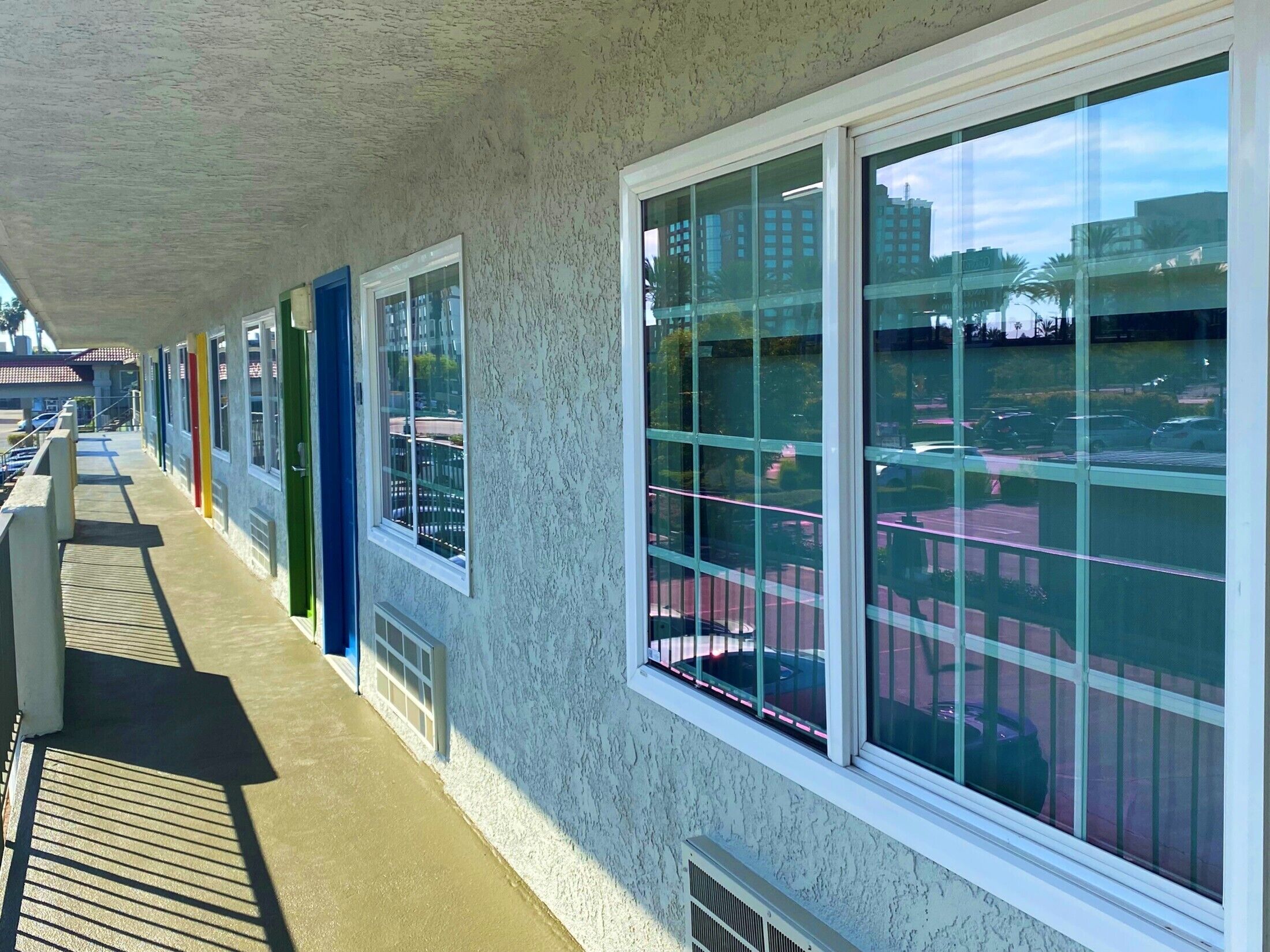 Un espacio al aire libre cubierto con una fila de ventanas que dan a un estacionamiento y edificios.