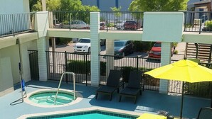 A swimming pool with a small hot tub, lounge chairs, and a yellow umbrella. - Bposhtels Anaheim (Anaheim)