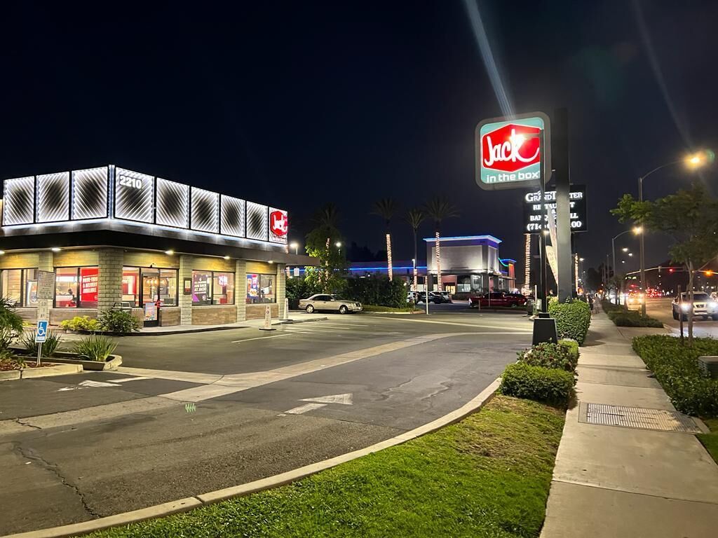 Un edificio del 2210 con un cartello di Jack in the Box, un parcheggio e una strada con semafori.