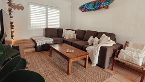 Ein Wohnzimmer mit braunem Sofa, einem Holztisch und einer farbenfrohen Wanddekoration.