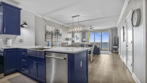 Une cuisine moderne dotée d’un îlot central, d’appareils électroménagers en acier inoxydable et de meubles de couleur bleue.
