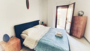 A bedroom with a bed, a nightstand, a dresser, and a window with a view. - Holiday Properties Terni Central Apartment (Terni)