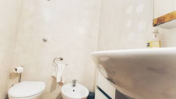 A bathroom with a toilet, bidet, and sink.