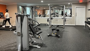 Une salle de sport équipée de machines de cardio, de matériel de musculation et dotée d’un mur recouvert de miroirs.
