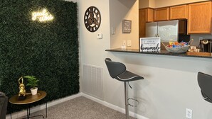 Une cuisine moderne avec des meubles en bois, un réfrigérateur en acier inoxydable et un néon mural.