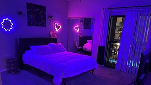 Une chambre à coucher avec un lit, une table de chevet, un miroir et une fenêtre avec des stores.