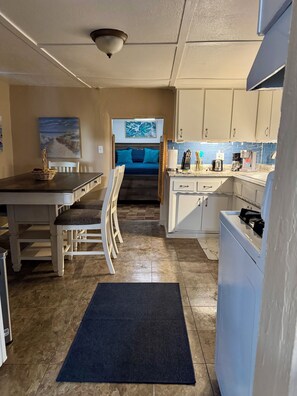 A compact kitchen with a dining area, a bed, and a view of the beach.