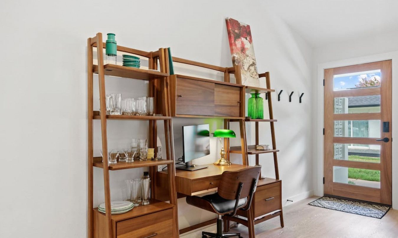 Un bureau à domicile équipé d’un bureau, d’une chaise, d’étagères et d’une porte donnant sur un beau paysage.