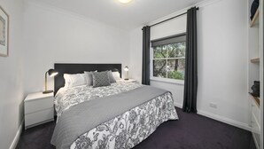 A bedroom with a large bed, a nightstand, a window with curtains, and a ceiling light. - 2 Bedroom Villa at Cypress Lakes Resort (Pokolbin)