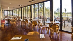A spacious indoor dining area with wooden tables and chairs, large windows offering views of the outdoors. - 2 Bedroom Villa at Cypress Lakes Resort (Pokolbin)