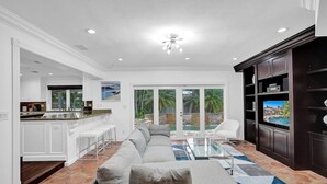 Ein modernes Wohnzimmer mit einem großen grauen Ecksofa, einem Glastisch und einem Fernseher auf einer dunklen Holzunterhaltungseinheit.