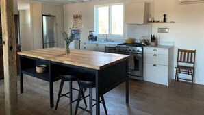 A modern kitchen with a central island, bar stools, a stove, and a refrigerator.