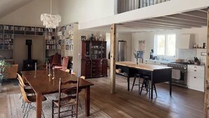 A spacious loft with a dining area, kitchen, and library.