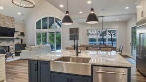Cucina spaziosa con un'isola grande, mobili scuri e illuminazione a sospensione.