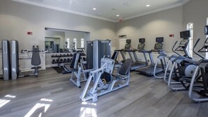 Ein Fitnessstudio mit verschiedenen Trainingsgeräten, Hanteln und einer Spiegelwand.