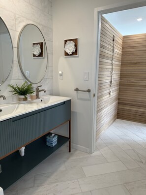 A modern bathroom with a large mirror, two sinks, a wooden vanity, and a shower area. - OCEANSIDE DUCK KEY HOUSE / BOAT RAMP & DOCK  (Marathon)