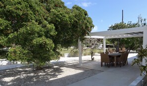 A covered outdoor seating area with a table and chairs, surrounded by trees and gravel. - OCEANSIDE DUCK KEY HOUSE / BOAT RAMP & DOCK  (Marathon)