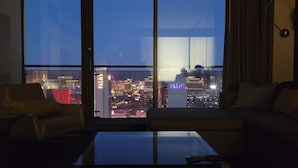 A modern living room with a large window overlooking a cityscape at night.