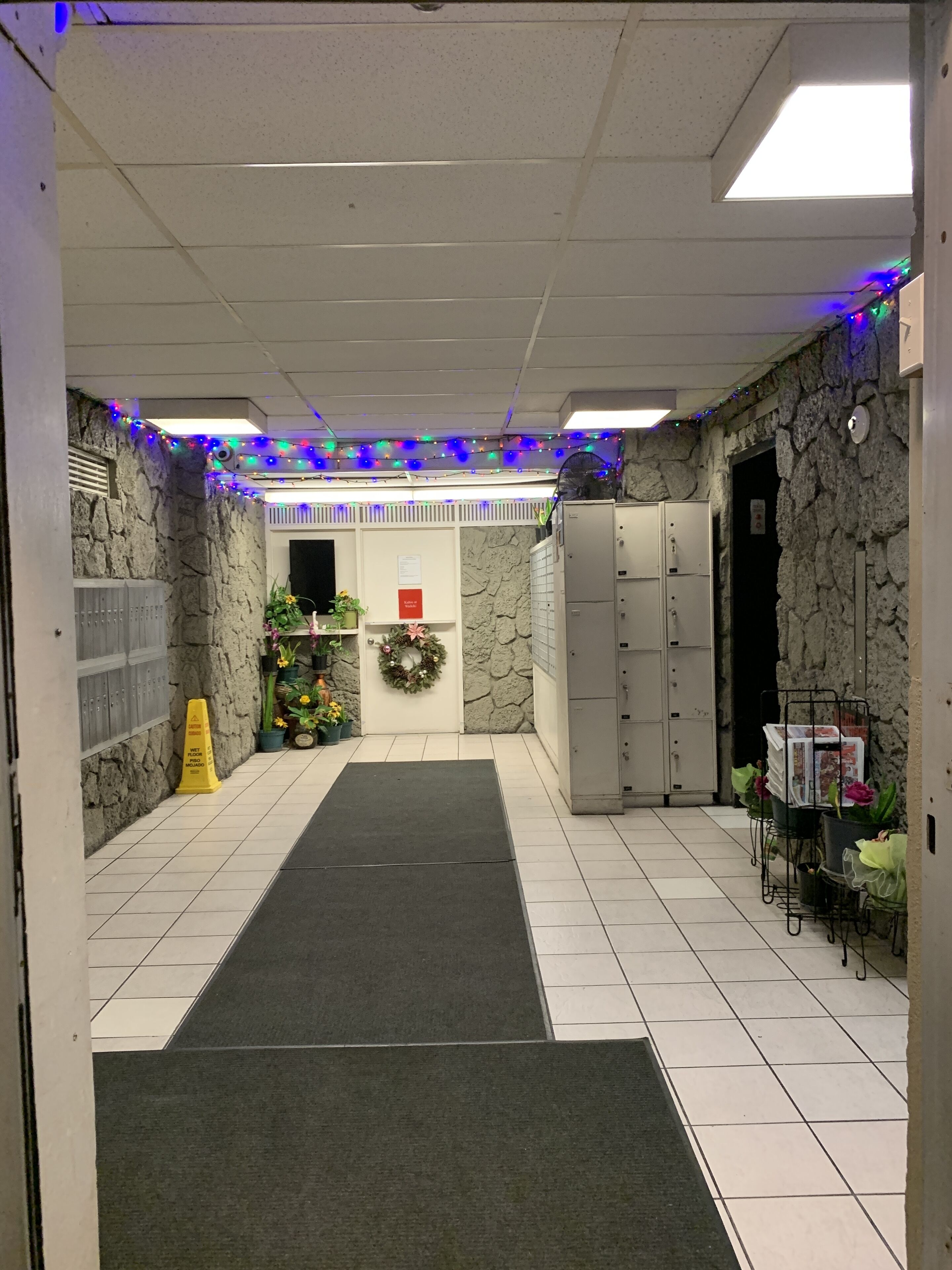 Un pasillo con pared de piedra, alfombra verde, taquillas y un adorno en la pared.