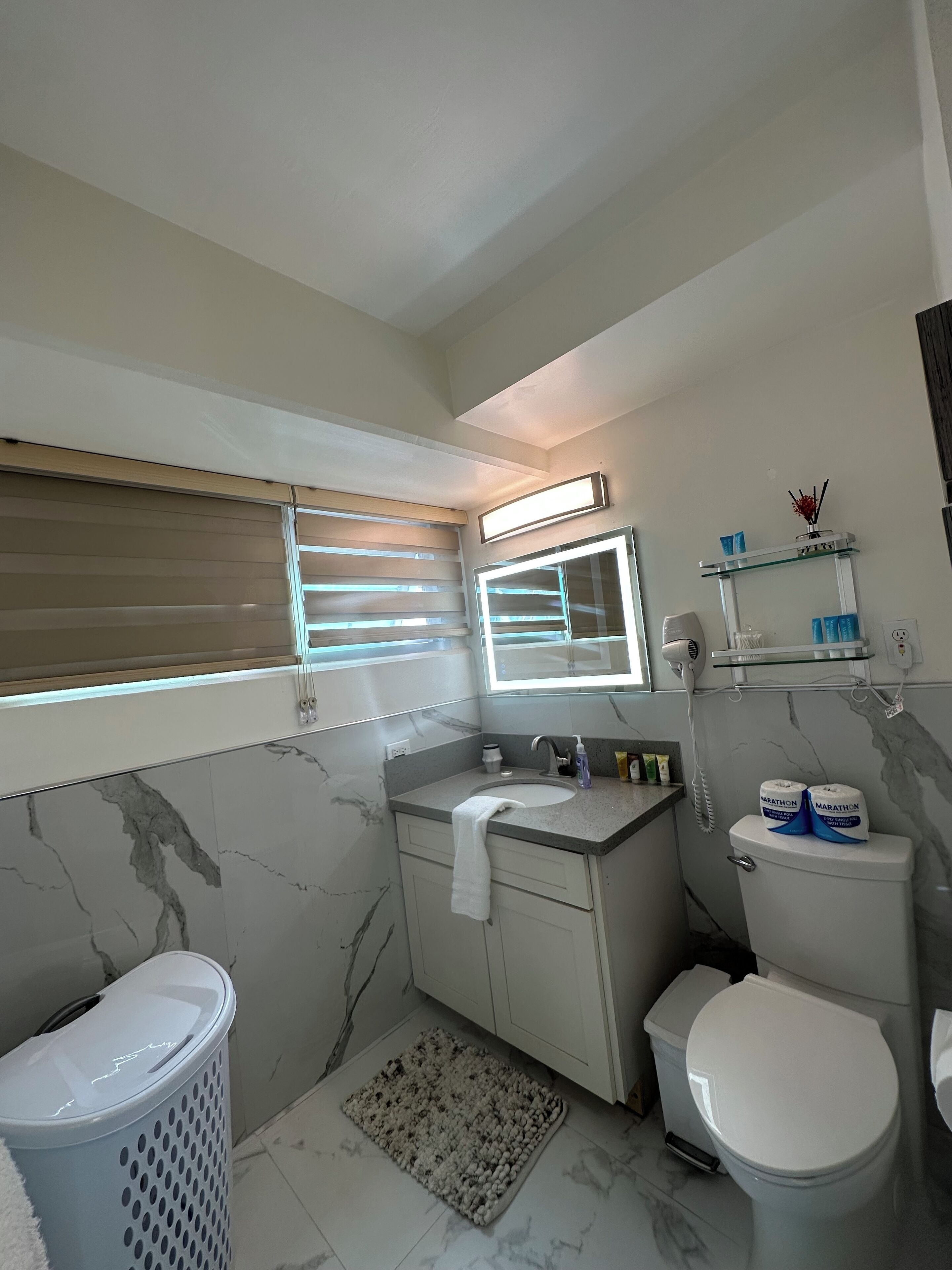 A bathroom with a toilet, sink, and a window with blinds.