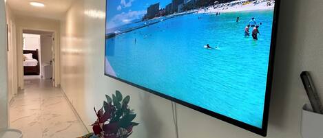 A flat-screen TV mounted on a wall displaying a beach scene.