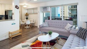 Een moderne woonkamer met een bank, een klein tafeltje en een eethoek met stoelen.