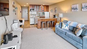 Un espacio habitable compacto con kitchenette, comedor y sofá con cojines decorativos.