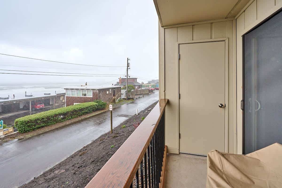 A balcony with a view of a street and buildings, a door, and a covered area.