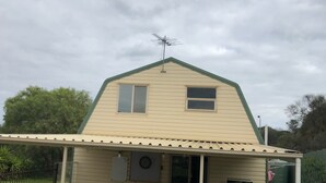 A single-story house with a covered patio area, a small window, and a satellite dish.