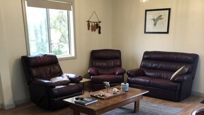 A living room with three leather sofas, a wooden coffee table, and a rug.