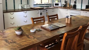 A kitchen with a wooden dining table, white cabinets, and a window providing natural light.