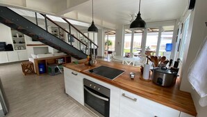 Une cuisine spacieuse dotée d’un plan de travail en bois, d’appareils électroménagers en acier inoxydable et d’un escalier menant à l’étage supérieur.