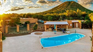 A backyard with a swimming pool, patio furniture, and a mountain in the background.